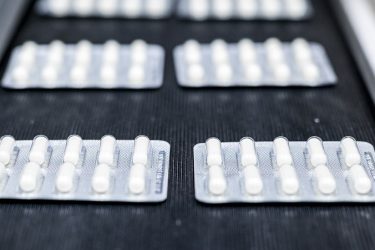 Pills in blister pack on conveyor belt in a pharmaceutical industry production