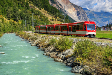Travelling by train (pictured running alongside a lake) can make for the perfect sustainable summer holiday.